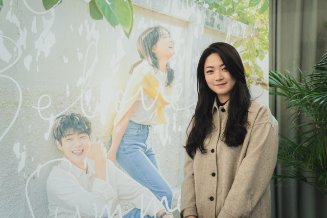 ‘그 해 우리는’의 각본을 쓴 이나은 작가가 드라마의 포스터 앞에서 포즈를 취하고 있다. /사진 제공=SBS