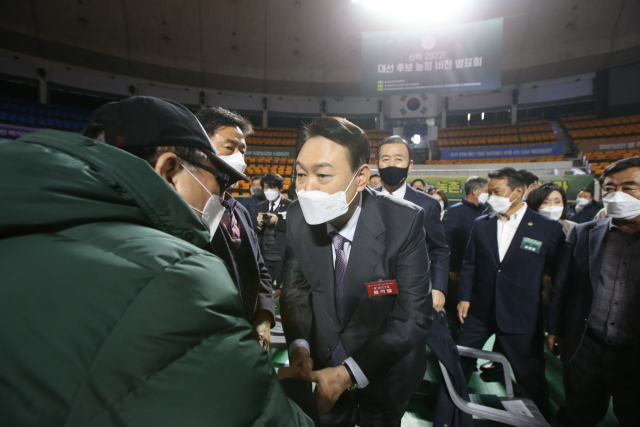 윤석열 국민의힘 대선 후보가 4일 오후 서울 송파구 잠실학생체육관에서 열린 한국농업경영인중앙연합회 주최 ‘선택 2022! 대선 후보 농정 비전 발표회’에서 한 참석자의 손을 잡고 인사하고 있다. /연합뉴스