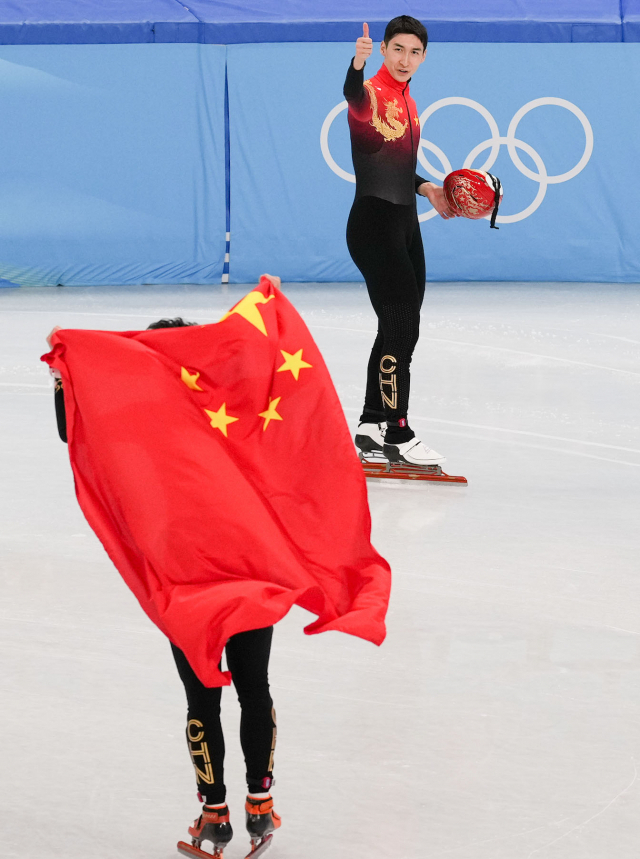 지난 7일 쇼트트랙 남자 1000m에서 우승한 뒤 중국 국기를 두른 런쯔웨이(왼쪽)를 향해 팀 동료 우다징이 엄지를 들어 보이고 있다. 신화연합뉴스