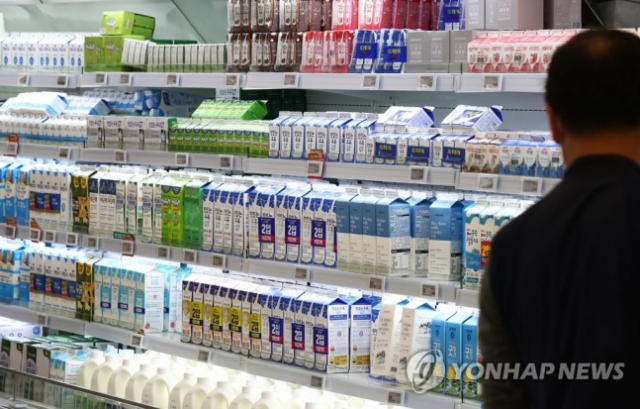 한 시민이 대형마트에서 우유를 고르고 있다. 연합뉴스