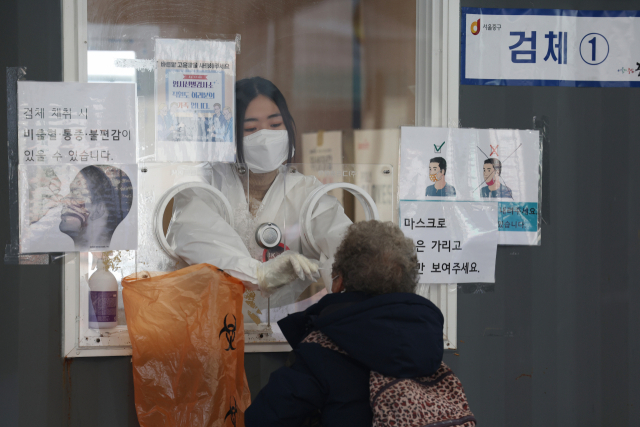 지난 12일 오전 서울 중구 서울역광장에 마련된 코로나19 임시 선별검사소에서 의료진이 검체를 채취하고 있다. /연합뉴스