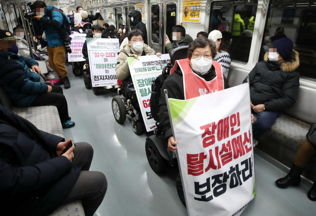 전국장애인차별철폐연대 관계자들이 지난달 3일 서울 지하철 5호선 광화문역에서 열린 '기획재정부 장애인권리예산 반영 촉구에 대한 입장발표 기자회견'을 마친뒤 열차에 탑승해 장애인 이동권 보장을 촉구하는 피케팅을 하고 있다./연합뉴스