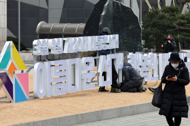 제20대 대선 공식 선거 운동 돌입을 하루 앞둔 14일 서울 중구 한국프레스센터 마당에 설치 중인 선거 홍보 조형물 앞으로 한 시민이 지나가고 있다./이호재기자