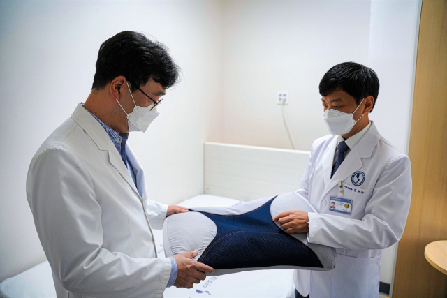 아주대병원 이비인후과의 김현준(오른쪽) 교수와 신경외과의 김상현 교수가 이브자리 기능성 베개를 살펴보고 있다. / 사진제공=이브자리