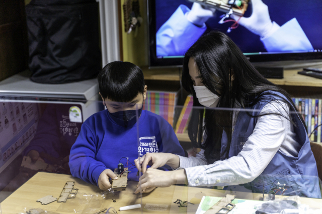 포스코케미칼 직원이 포항 지역아동센터에서 진행된 푸른꿈 환경학교에서 어린이와 함께 전기차 모형을 조립하고 있다. 사진 제공=포스코케미칼