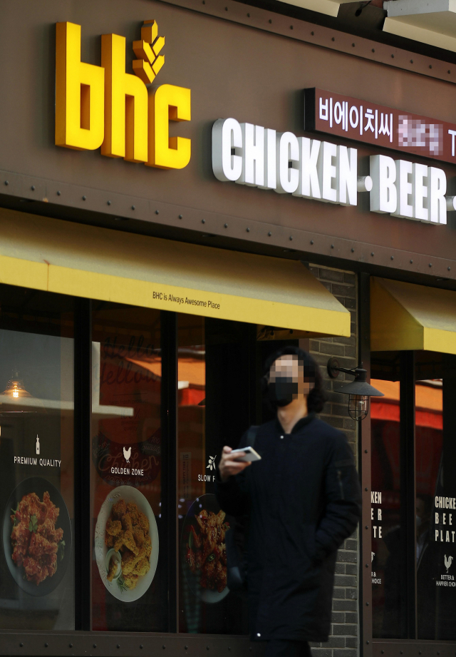 지난해 제품 가격을 인상한 한 프랜차이즈 치킨 업체 앞으로 시민이 지나가고 있다. /연합뉴스