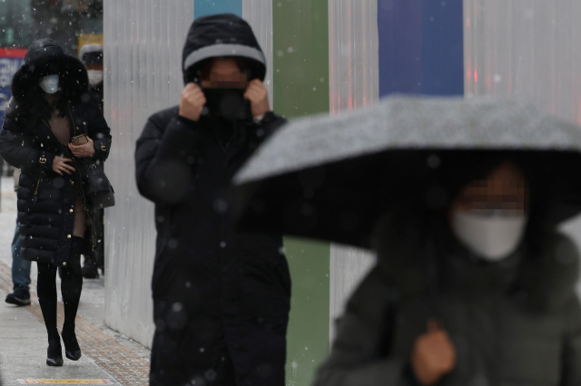 지난 15일 오전 서울 중구 을지로입구역 인근에서 시민들이 눈을 맞으며 걷고 있다. 연합뉴스