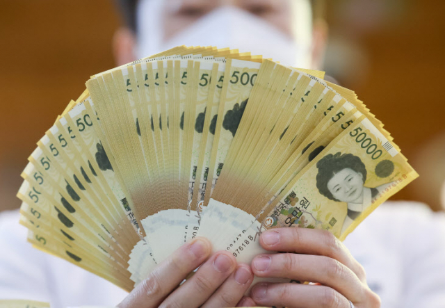 서울 중구 하나은행에서 직원이 5만원권을 펼쳐보이고 있다. /연합뉴스