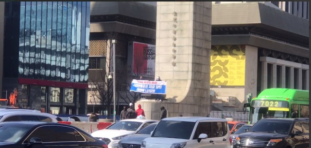 택배노동자들이 22일 서울 광화문 이순신 장군 동상 위에서 기습 시위를 벌였다. 사진제공=택배노조