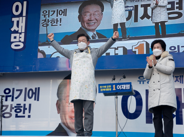 이재명(왼쪽) 더불어민주당 대선 후보가 22일 인천 부평역 광장에서 열린 유세에서 한 지지자로부터 앞치마를 선물받은 후 손을 들어 인사하고 있다. 성형주 기자