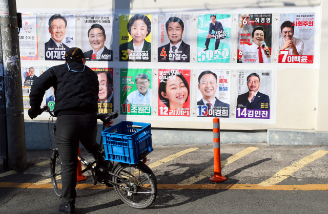 자전거를 탄 시민이 대구 시내에 부착된 제20대 대통령 선거 후보자 벽보를 22일 살펴보고 있다. 대구=연합뉴스