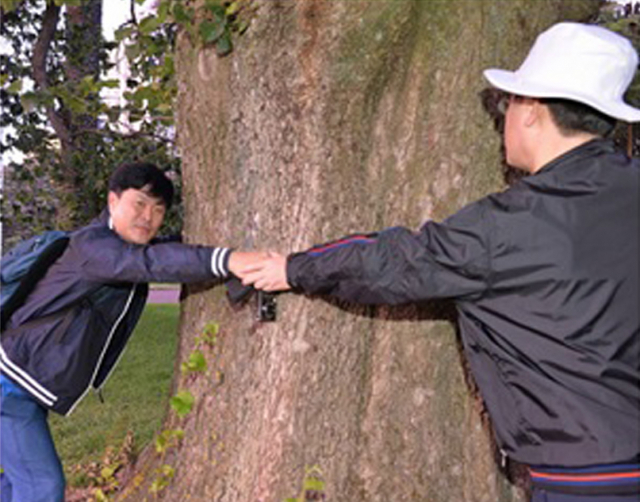 이재명 더불어민주당 대선후보(오른쪽)와 고 김문기 성남도시개발공사 개발1처장이 2015년 1월 뉴질랜드 출장 당시 손을 잡고 나무를 안은 채 찍은 사진. /사진 제공=김 전 처장 유족