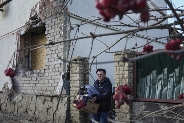 23일(현지시간) 우크라이나 동부 도네츠크주의 노보루한스크에서 한 남성이 포격으로 벽에 구멍 뚫린 주택에서 가재도구를 챙겨 나오고 있다. /연합뉴스