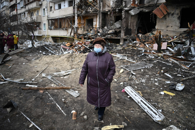 25일 한 우크라이나 여성이 수도 키예프에서 심하게 훼손된 건물 앞을 지나고 있다. /AFP연합뉴스