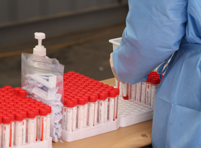 최근 코로나19 확진자 급증으로 유전자증폭(PCR) 검사 역량이 최대치에 달한 가운데 25일 오전 코로나19 한 임시선별검사소에 검체 채취 샘플이 쌓여 있다. /연합뉴스