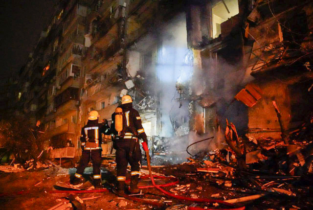 러시아의 우크라이나 침공 이틀째인 25일(현지시간) 우크라이나 소방대원들이 수도 키예프에서 로켓 공격을 받은 한 건물의 피해 상황을 살피고 있다. /연합뉴스