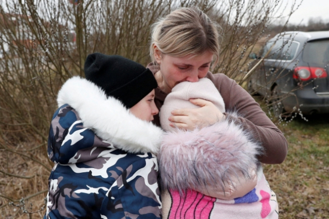 우크라이나인 안나 세먹(33)이 낯선 아주머니와 함께 우크라이나 국경을 넘은 아이들을 헝가리 쪽 초소 근처에서 만나 품에 안고 있다./로이터통신 연합뉴스