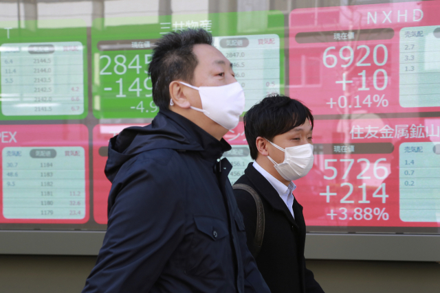 28일 도쿄 시민들이 마스크를 쓴 채 증권사 앞을 지나가고 있다. AP연합뉴스