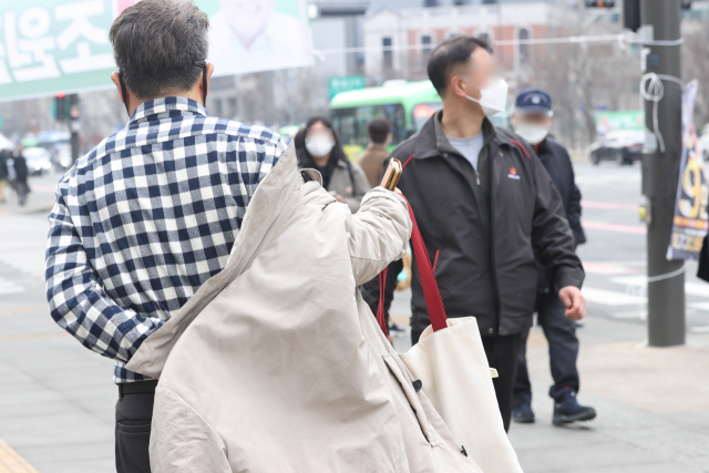 서울지역 낮 최고기온이 11도까지 올라 큰 일교차를 보인 지난 28일 오후 서울 광화문역 인근에서 시민이 들고 있던 옷을 입고 있다. 연합뉴스
