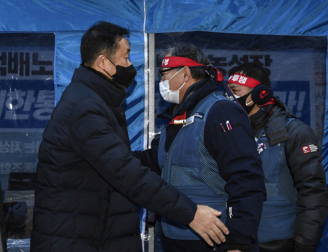 지난달 23일 오후 서울 중구 CJ대한통운 농성장에서 김종철 CJ대한통운대리점연합회(왼쪽)과 진경호 민주노총 전국택배노동조합 위원장이 공식 만남을 가진 뒤 악수하고 있다. 연합뉴스