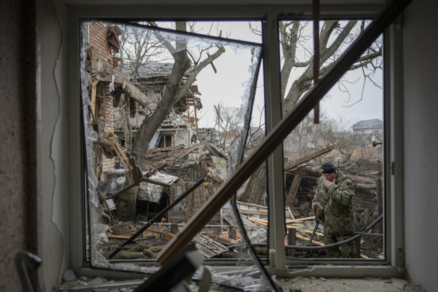러시아군의 포격이 이어진 2일(현지 시간) 우크라이나 수도 키이우(키예프) 외곽의 고렌카 지역에서 한 민병대가 포격으로 폐허가 된 민가의 잔해를 살펴보고 있다. AP연합뉴스