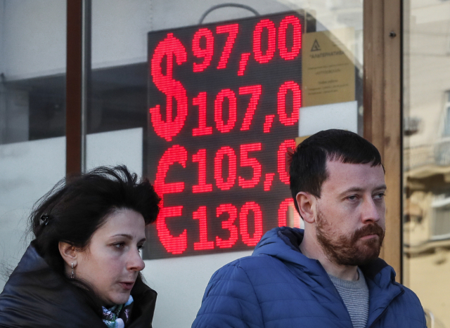 지난 2일(현지 시간) 러시아 모스크바 시내 외환거래소에서 행인들이 유로·달러화에 대한 루블화 환율을 표시하는 전광판 앞을 지나가고 있다. EPA연합뉴스