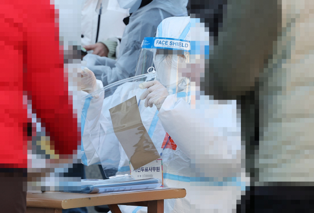 5일 서울역 앞 임시기표소에서 코로나19 확진·격리자들이 투표를 한 뒤 기표용지를 투명한 비닐 팩에 담고 있다. / 연합뉴스