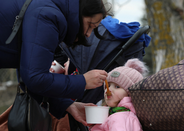 지난 6일(현지시간) 몰도바 투도라의 국경 건널목에서 한 여성이 우크라이나에서 몰도바로 도망친 뒤 아이에게 음식을 먹이고 있다./ 로이터 연합뉴스