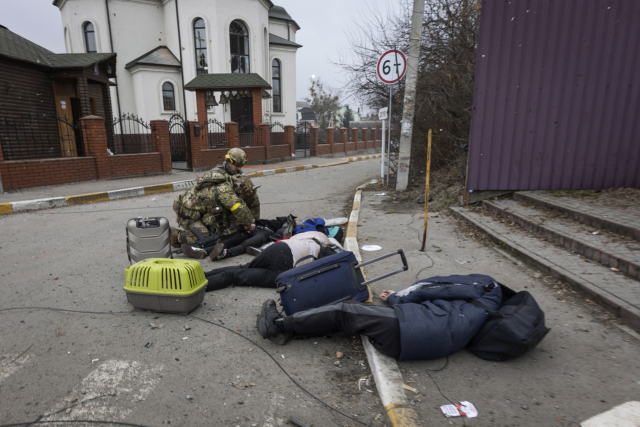 6일(현지 시간) 우크라이나 수도 키이우(키예프) 외곽 도시 이르핀에서 우크라이나 군인들이 피란길에 올랐다 러시아군의 공격을 받고 쓰러진 일가족을 살펴보고 있다. AP연합뉴스