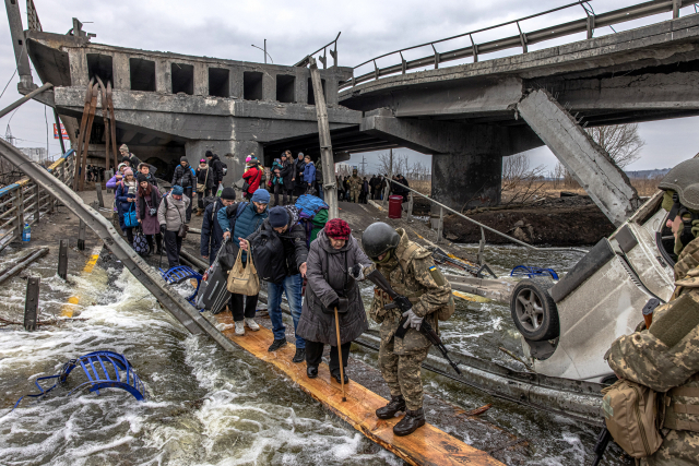 7일(현지 시간) 우크라이나 수도 키이우(키예프) 외곽 이르핀강에 있는 다리가 러시아의 포격으로 파괴되자 피란민들이 우크라이나군의 도움을 받으며 다리 아래에 설치된 임시 통로로 강을 건너고 있다. EPA연합뉴스
