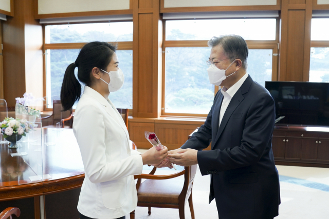 8일 문재인 대통령이 청와대 집무실에서 김현지 간호장교에게 ‘세계 여성의 날을 축하하며 당신을 응원합니다’라는 메시지가 담긴 장미꽃과 함께 격려의 말을 전하고 있다. /연합뉴스