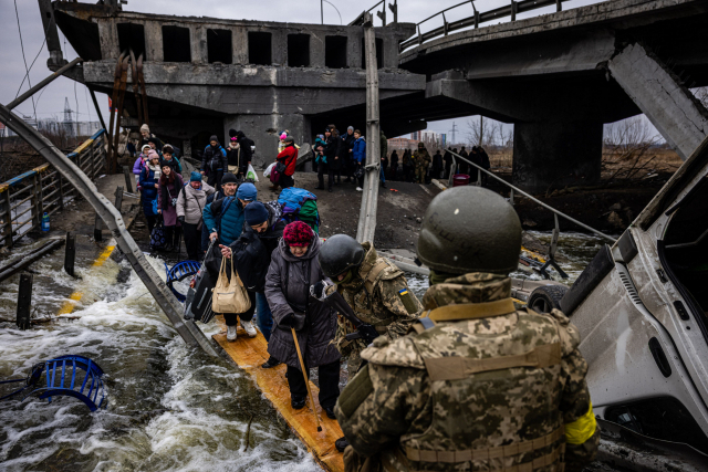 7일(현지 시간) 우크라이나 수도권인 키이우 북서쪽 이르핀 주민들이 러시아군의 폭격으로 파괴된 다리를 건너 피란하고 있다. 러시아군은 수도 키이우 북쪽 외곽 도시에 대한 공세를 강화하면서 사상자가 늘어나고 전기·수도·난방이 모두 끊기자 주민들의 탈출 행렬이 이어지고 있다. 연합뉴스