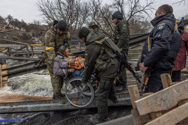 우크라이나 키이우(키예프) 인근 도시 이르핀에서 우크라이 군인들이 휠체어를 타고 피란길에 나선 한 할머니를 도와주고 있다. 러시아의 무차별 공격으로 이 지역의 전기·수도·난방이 모두 끊기면서 주민들이 필사의 피란 행렬에 나섰다. EPA연합뉴스