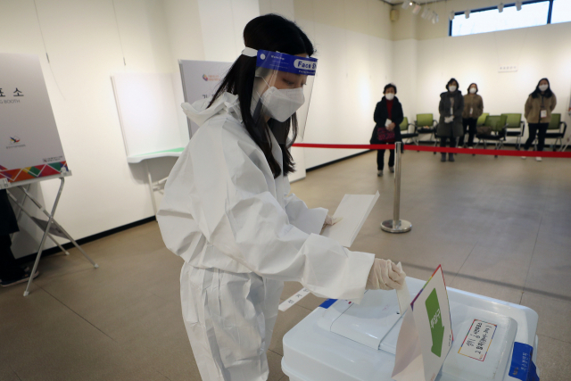 지난 5일 오후 광주 서구 학생교육문화회관에 마련된 상무1동 사전투표소에서 확진·격리자들이 투표한 투표용지를 방역복을 입은 관계자가 전달받아 투표함에 넣고 있다. 본투표에서는 유권자가 일반 유권자가 이용한 투표함에 투표용지를 직접 투입하면 된다. 연합뉴스