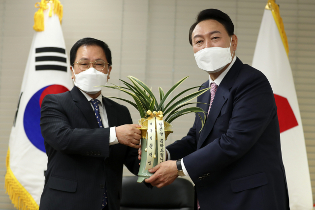 윤석열 대통령 당선인이 10일 오후 서울 여의도 국민의힘 당사에서 유영민 대통령 비서실장으로부터 문재인 대통령의 축하난을 받고 있다. 성형주 기자