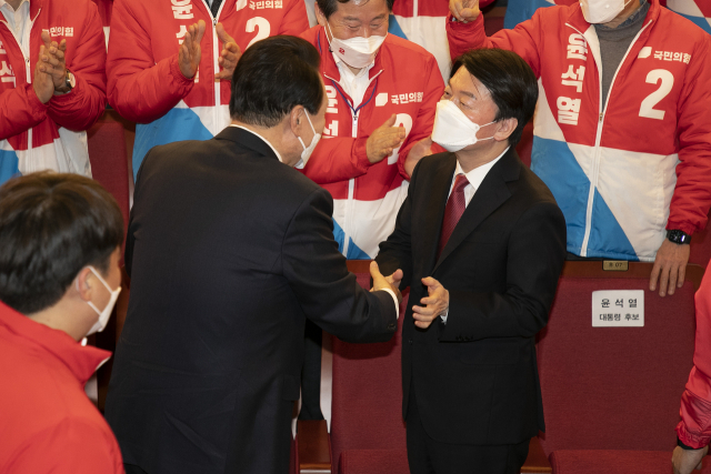 윤석열 제20대 대통령 당선인이 10일 새벽 서울 여의도 국회도서관에 마련된 \'국민의힘 제 20대 대통령선거 개표상황실\'에서 국민의당 안철수 대표와 함께 악수하고 있다./성형주 기자