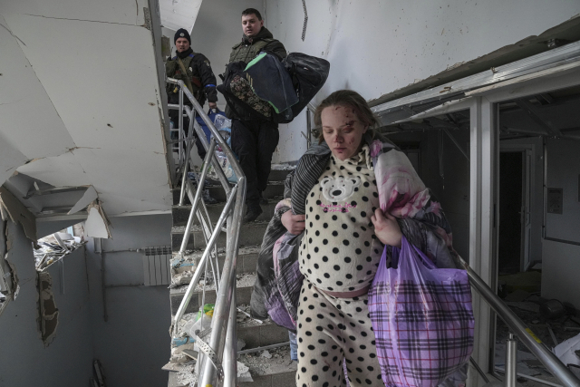 9일(현지 시간) 우크라이나 남부 마리우폴에서 한 임신부가 러시아군의 포격으로 초토화된 산부인과에서 서둘러 나오고 있다. AP연합뉴스