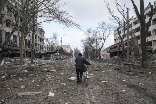 우크라이나 남부 마리우폴에서 10일(현지 시간) 한 남성이 러시아군의 포격으로 초토환된 거리를 자전거를 끌고 지나가고 있다. A=연합뉴스