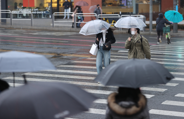 지난달 서울 마포구 홍대 거리에서 우산을 쓴 시민들이 길을 건너고 있다. 연합뉴스