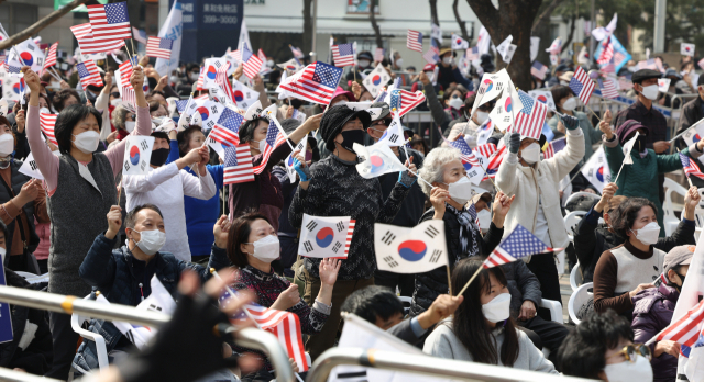 코로나19 신규 확진이 팬데믹 이후 최다를 기록한 12일 오후 서울 중구 감리교 회관 앞에서 전광훈 사랑제일교회 담임 목사가 대표로 있는 국민혁명당 주최로 열린 1천만 자유 통일 기도회에서 참석자들이 태극기와 성조기를 흔들며 찬송을 부르고 있다. /연합뉴스