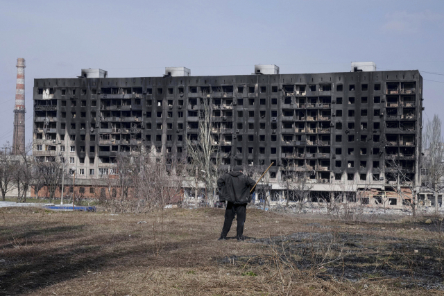 13일(현지시간) 한 남성이 우크라이나 마리우폴에서 포격으로 파손된 불탄 아파트 건물을 바라보고 있다. AP연합뉴스