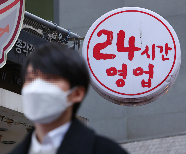 지난 4일 오후 서울 종로에서 한 시민이 24시간 영업 간판 아래를 지나고 있다. 연합뉴스