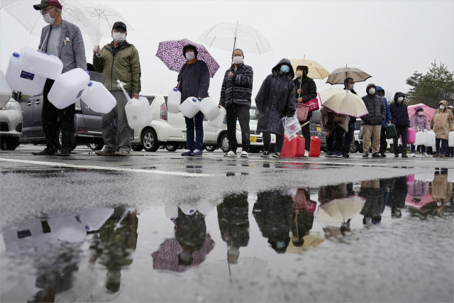 18일(현지시간) 일본 후쿠시마현 미나미소마시의 시민들이 음용수를 받기 위해 비를 맞으며 줄을 서 있다. 이틀 전 발생한 대지진으로 이 지역에서 음용수 공급이 중단됐다. 미나미소마 로이터=연합뉴스