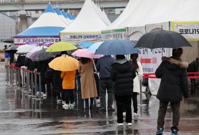 주말인 19일 비가 내리는 가운데 서울역 임시 선별검사소에서 우산을 쓴 시민들이 검사를 기다리고 있다. /연합뉴스
