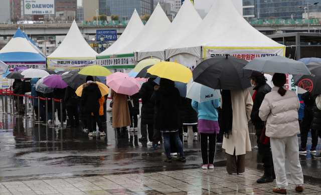 주말인 19일 비가 내리는 가운데 임시 선별검사소에 우산을 쓴 시민들이 검사를 기다리고 있다./연합뉴스