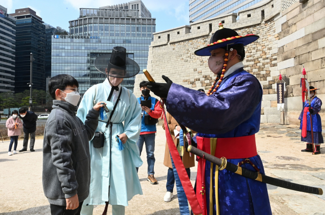 20일 서울 중구 숭례문에서 열린 '숭례문 호패놀이' 행사에 참가한 어린이들이 파수꾼에게 호패를 꺼내 보이고 있다. 호패놀이는 조선시대 신분증과 같은 호패를 직접 만들어 파수대장에게 보여주고 숭례문을 통과하는 체험 행사로 4월10일까지 매주 주말마다 열린다./권욱 기자 2022.03.20