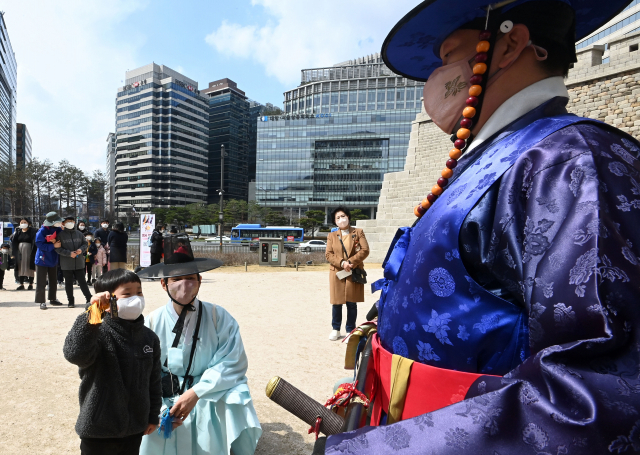 20일 서울 중구 숭례문에서 열린 '숭례문 호패놀이' 행사에 참가한 어린이들이 파수꾼에게 호패를 꺼내 보이고 있다. 호패놀이는 조선시대 신분증과 같은 호패를 직접 만들어 파수대장에게 보여주고 숭례문을 통과하는 체험 행사로 4월10일까지 매주 주말마다 열린다./권욱 기자 2022.03.20