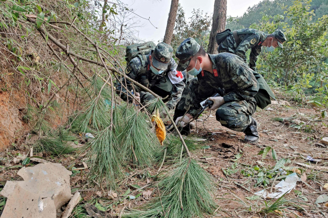 군인들이 중국 남부 광시좡족자치구 우저우시 텅현 산중턱에 21일 추락한 중국 동방항공 여객기의 잔해 등을 수색하고 있다. AFP연합