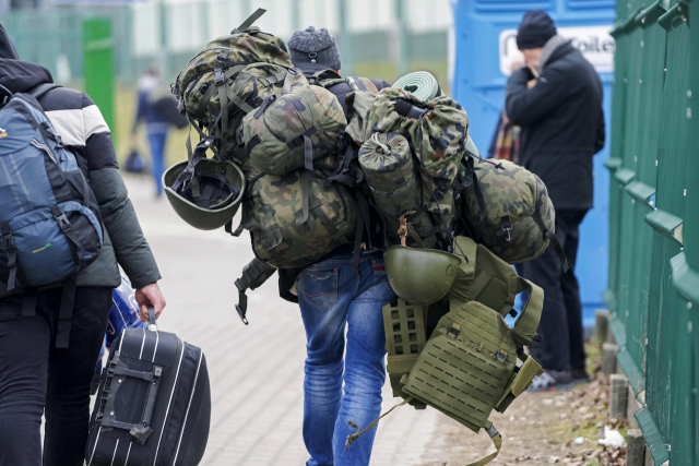 폴란드 남동부 메디카에서 한 남성이 전투 장비가 잔뜩 담긴 군장을 메고 우크라이나로 가는 국경을 넘고 있다. AP 연합뉴스