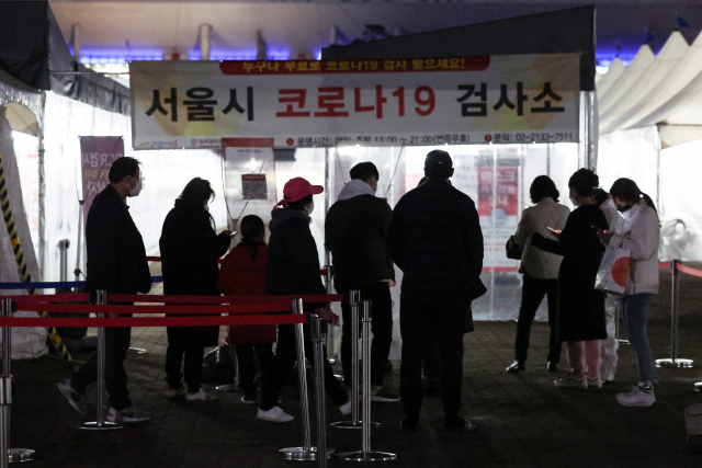 지난 22일 오후 서울 마포구 월드컵공원 평화광장 임시선별검사소에서 피검자들이 줄을 서 있다. 연합뉴스